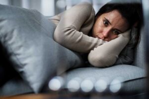 a person looks extremely sad lying on a couch possibly thinking of the links between depression and aging