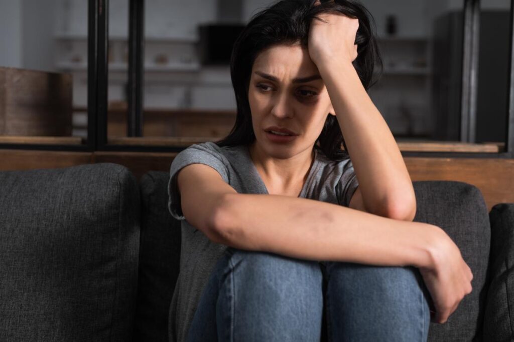 woman sitting on floor looking distressed while dealing with trauma and relationships