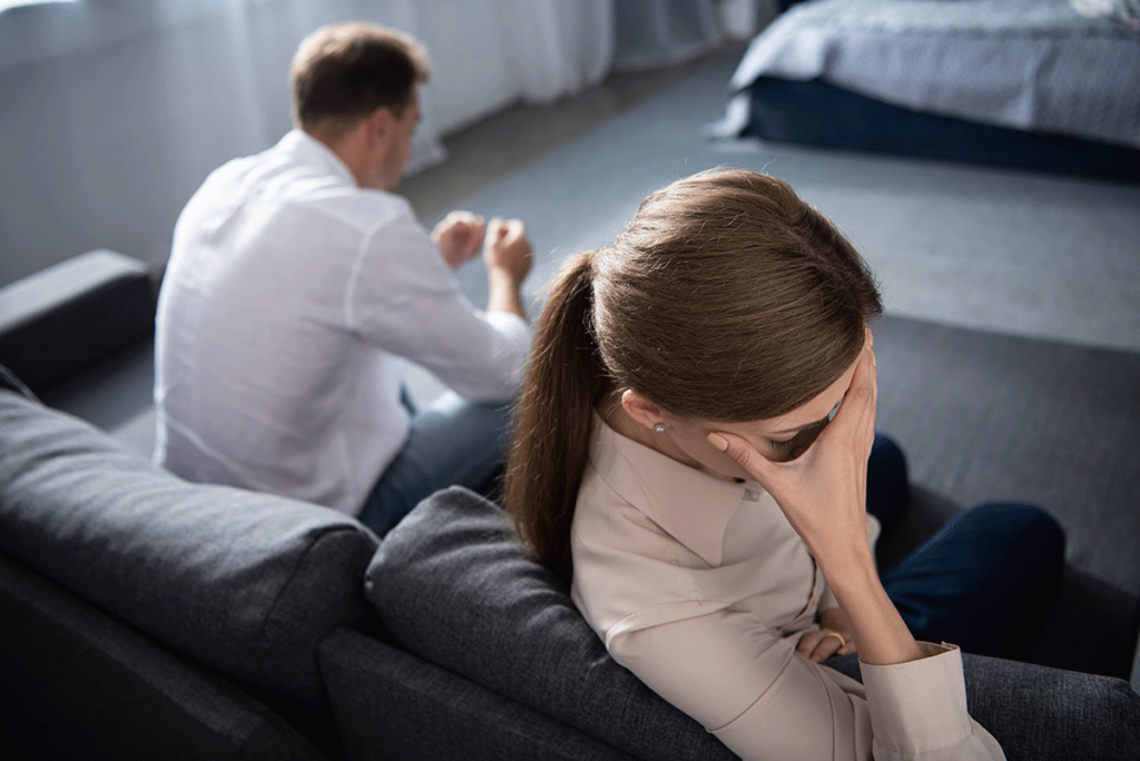 couple sitting on couch having an argument at work while trying to understand trauma and relationships