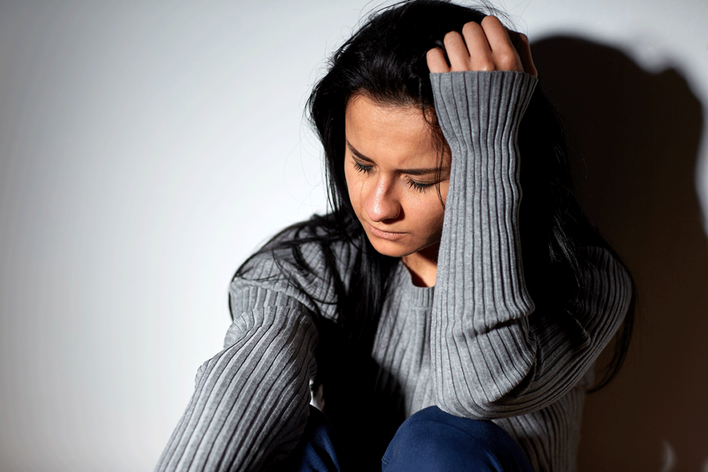 person sitting against wall looking distressed while dealing with side effects of meth