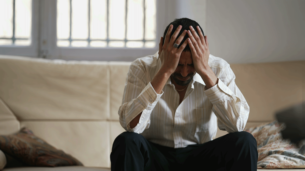 person sitting on couch with head in hands experiencing cocaine addiction and depression