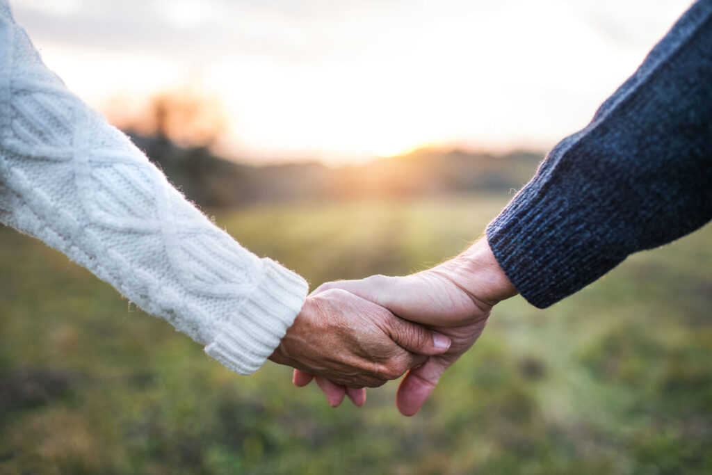 people holding hands while walking through field at sundown after working through codependent relationships