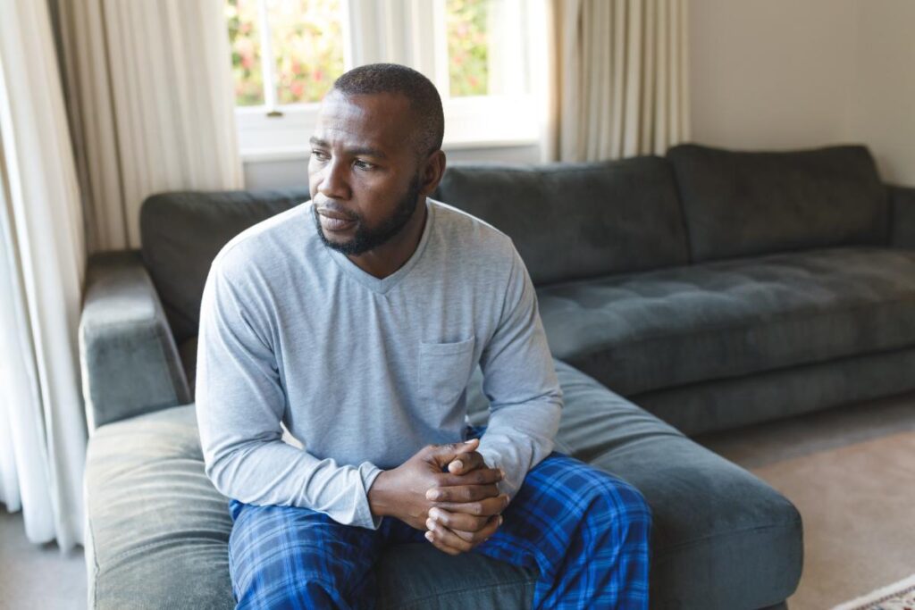 person sitting on couch with faraway look while wondering what is dysthymia