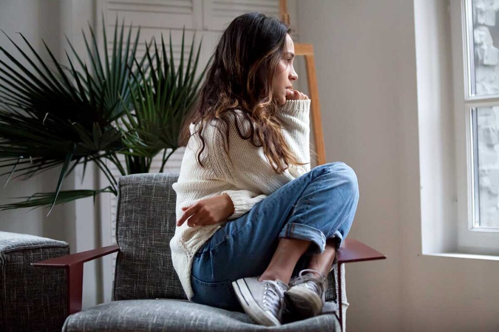 person sitting on chair looking out window while contemplating porn addiction in women